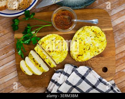 Kreuzkümmelkäse mit ausgeschnittenem Segment auf Holzbrett mit Rosmarin und Kreuzkümmel Stockfoto