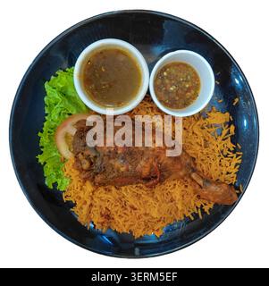 Blick von oben auf die traditionelle arabische Nasi Mandy serviert mit einem gerösteten Hühnerviertel, würzigem Sambal, herzhafter Suppe Soße, frischem Salat und Tomatenscheibe auf i Stockfoto