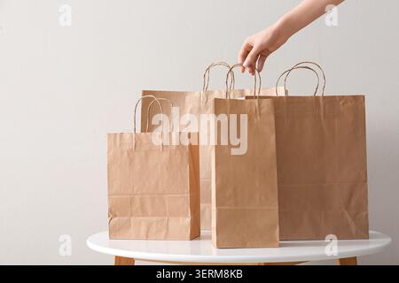 Nachhaltige Einzelhandelsverpackungen: Frauen legen von Hand braune Papiertaschen auf weißen Tisch, umweltfreundlicher Handel Stockfoto