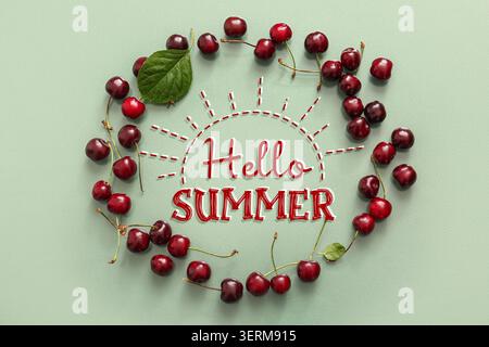 Hallo Sommertext mit frischen roten Kirschen und grünem Blatt in Sonnenform auf hellgrünem Hintergrund Stockfoto