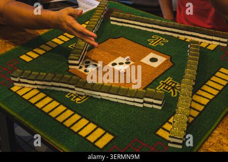 Ein traditionelles Mahjong-Spiel, bei dem Spieler zwei Würfel auf einer grünen Stoffmatte Rollen. Stockfoto