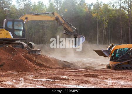 Schwere Maschinen graben Schmutz auf der Baustelle, umgeben von Bäumen in bewaldeten Gebieten Stockfoto