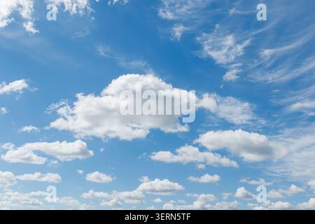 Eine weite Landschaftsansicht, die einen lebendigen, tiefblauen Himmel mit strukturierten, flauschigen weißen Cumulus-Wolken in verschiedenen Höhen und dünnen, zerklüfteten Zirren einfängt Stockfoto
