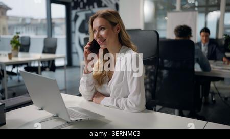 Erfolgreiche kaukasische Geschäftsfrau, die einen Laptop schreibt und einen Anruf am Tisch im Büro entgegennimmt Geschäftsfrau spricht CEO weibliche Arbeit Stockfoto