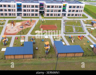 Blick aus der Vogelperspektive auf ein modernes Schulgebäude mit einem großen farbenfrohen Spielplatz Stockfoto