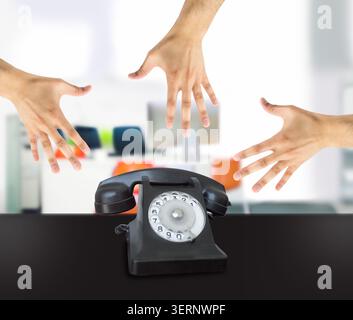 Eine Gruppe von Händen schnappt sich ein altes Telefon im Büro Stockfoto