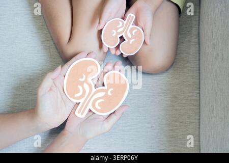 Weltnierentag. Erwachsene und Kinder halten nierenförmiges Papier zu Hause. Nationaler Organspendertag. Nierengesundheitskonzept. Stockfoto