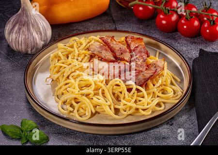 Appetitliche italienische Pasta Carbonara serviert auf rustikalem Teller. Das Gericht umfasst Spaghetti, knusprigen Speck und Parmesan Stockfoto