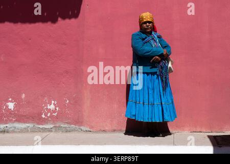 Eine Raramuri-Frau, die vor einer roten Mauer steht Stockfoto