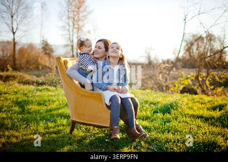 Mutter mit Tochter und Baby auf einem Sessel draußen Stockfoto