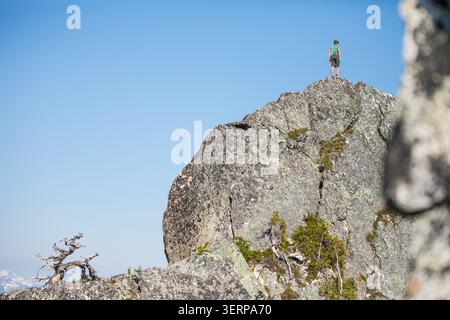 Der Mann steht auf einem felsigen Berggipfel Stockfoto