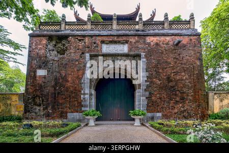Doan Mon Tor, Kaiserliche Zitadelle von Thang Long, ein altes Backsteintor mit einem bogenförmigen Eingang und traditionellem Dach, umgeben von grünem Laub in Hanoi, Vietnam Stockfoto
