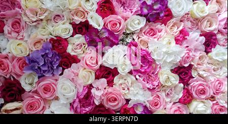 Helle Blumen bedecken eine Wand in einer Ausstellung verschiedener Farben und Arten während einer Feier in einem öffentlichen Raum am Nachmittag Stockfoto