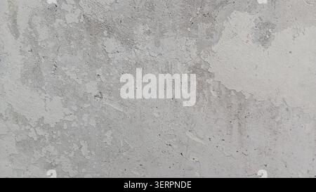 Nahaufnahme der rauen Betonwand mit verschiedenen Texturen und Farben, die Anzeichen von Verschleiß und Alterung an einem sonnigen Tag in einer städtischen Umgebung zeigen Stockfoto