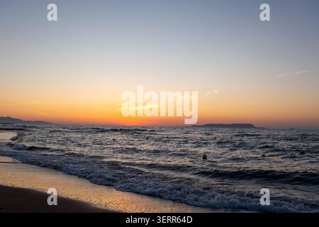 Ein Panoramablick auf ein wunderschönes Nachglühen über dem Ozean Horizont kurz nach Sonnenuntergang. Der helle orange Abendhimmel steht im Kontrast zu der dunklen, kräuselnden se Stockfoto