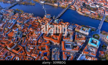 Drohnenblick auf die roten Dächer der Prager Altstadt entlang der Moldau und der Karlsbrücke, Tschechische Republik, Herbst Stockfoto