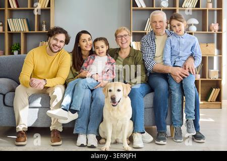 Glückliche Mehrgenerationsfamilie mit labrador zu Hause, fröhliches Porträt Stockfoto