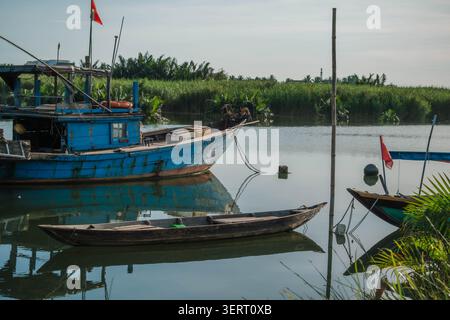 Traditionelle Holzboote, die an einem ruhigen Flusskanal in einer tropischen Gegend vertäut sind Stockfoto