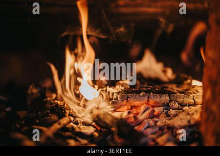 Nahaufnahme von glühender Glut und tanzenden Flammen über verkohltem Holz in einem warmen Kamin Stockfoto