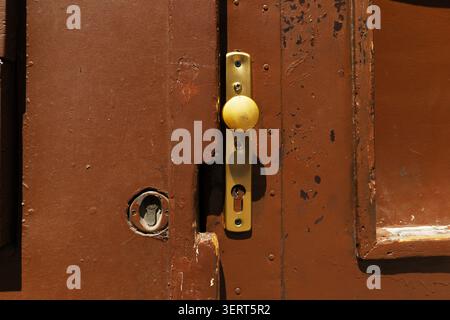 Alter alter alter alter Metalltürgriff an einem braun lackierten Holztor Stockfoto