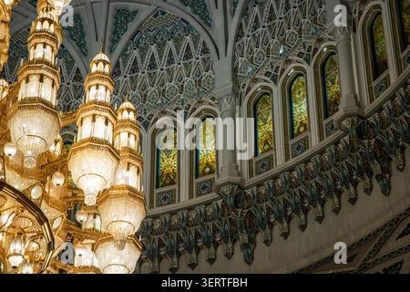 Blick auf die kunstvollen Kristallleuchter und die komplizierte Mosaikdecke in der Sultan-Qaboos-Moschee in Maskat, Maskat Governorate, Oman. Stockfoto
