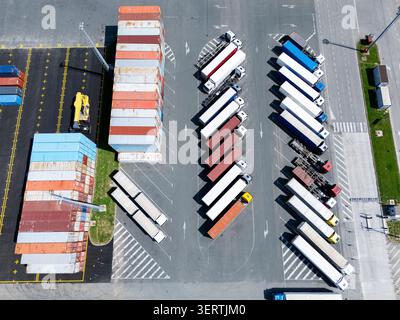 Luftaufnahme eines Logistikzentrums mit mehrfarbigen Versandcontainern und Lkws Stockfoto