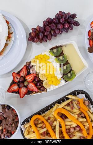 Overhead Shot enthält Acai-Creme mit Belag: Erdbeere, Trauben, Bananen, Mango, Kiwi, Tapioka, Schokoladencreme und Pommes frites. Neutraler Hintergrund Stockfoto