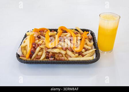 Pommes frites mit Speck, Käsesauce und Orangensaft, serviert im Korb. Studio auf weißem Hintergrund, helle und lebendige Farben. Perfekt für fas Stockfoto