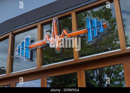 Rotterdam, Niederlande - 03. Juni 2026: Leuchtendes Neonschild, das eine blaue Langhantel und eine orangene Herzschlaglinie auf einem Glasfenster eines Fitnesscenters kombiniert Stockfoto