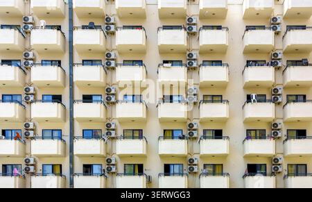 Fassade eines Wohngebäudes mit zahlreichen Balkonen und Klimaanlagen, die ein modernes urbanes Wohnumfeld hervorheben Stockfoto