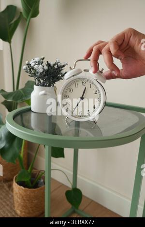 Hand zum Ausschalten des Weckers am Nachttisch Stockfoto