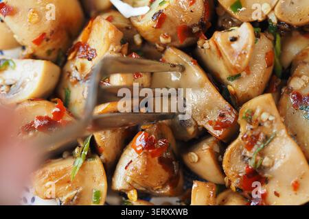 In Scheiben geschnittene Pilze mit Knoblauchsoße und Gewürzen auf einem Teller Stockfoto