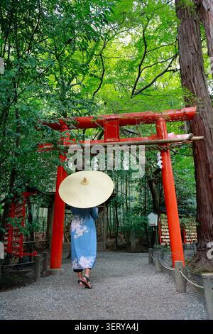 Frau im Kimono mit einem Wagasa-Regenschirm vor dem roten Torii-Tor am Kamigamo-Schrein in Kyoto, Japan Stockfoto