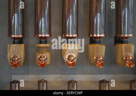 Moderne Kaffeebohnenspender mit Kupfer- und Holzdesign in einem Café-Interieur Stockfoto