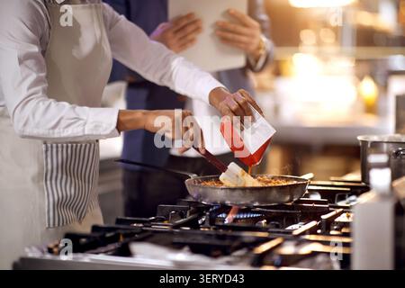 Mischen Sie Tomatensauce mit Fleisch in der Pfanne. Kochen Sie in professioneller, moderner Küche, Restaurant-Konzept Stockfoto