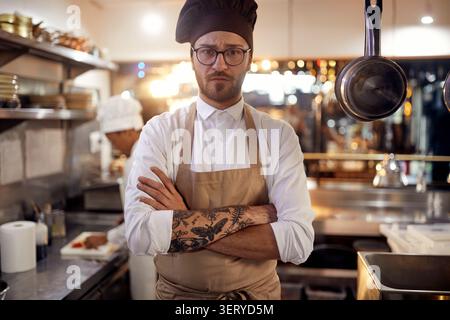 Kochen Sie in professioneller, moderner Küche, Restaurant-Konzept. Männlicher Koch, der in die Kamera schaut Stockfoto