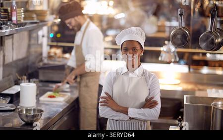 Wunderschönes weibliches Porträt der Küchenchefin. Kochen Sie in professioneller, moderner Küche, Restaurant-Konzept Stockfoto