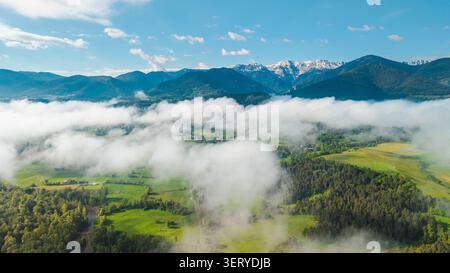 Aus der Vogelperspektive der nebeligen Pyrenäen und der grünen Landschaft in Katalonien Spanien mit niedrigen Wolken, die über Wäldern und Feldern schweben Stockfoto