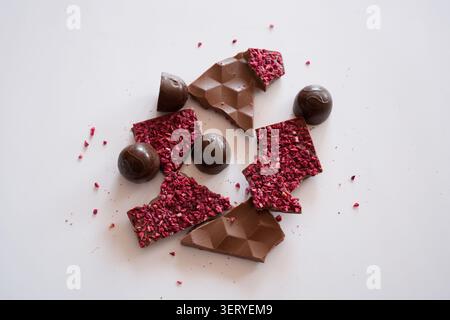 Eine Komposition handgemachter Süßwaren auf isoliertem weißem Hintergrund. In der Mitte befinden sich große Stücke Milchschokolade, runde und quadratische Schokolade Stockfoto