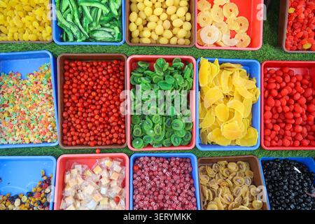 Blick von oben auf getrocknete Kiwi, Mango, Ananas und bunte kandierte Früchte in Tabletts an einem lokalen Marktstand in Kaschmir, Indien. Stockfoto