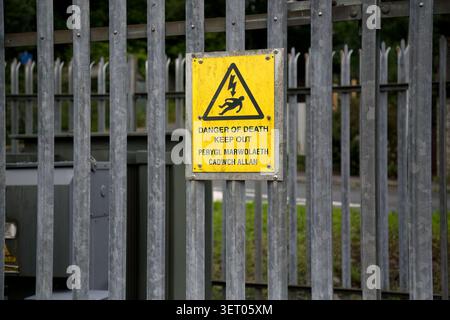 Ein gelbes zweisprachiges Warnzeichen für die Gefahr des Stromtodes in Wales. Stockfoto