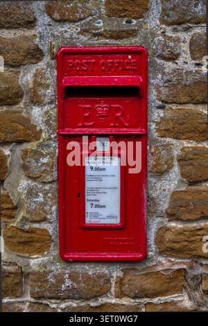 Roter Postkasten in einer Karrsteinmauer Stockfoto