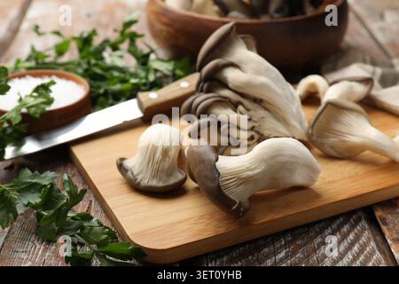 Frische Austernpilze, Salz und Petersilie auf Holztisch, Nahaufnahme Stockfoto