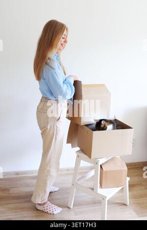 Modernes Lifestyle-Bild einer jungen Frau, die mit ihrer Katze umzieht, wobei Eigenheimbesitz und Lebensveränderungen hervorgehoben werden. Stockfoto