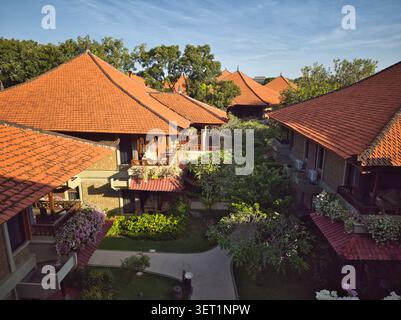 Schöne tropische Resort-Architektur mit orangefarbenen Ziegeldächern und üppigen Gärten in Medewi, Bali. Stockfoto