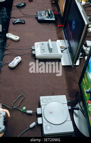 Retro-Spielekonsolen mit klassischen Controllern und CRT-Monitoren auf dem Tisch Stockfoto