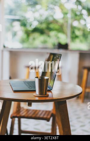 Gemütliche Café-Ecke in Tokio, Japan – Holztisch mit Laptop und Edelstahlbecher, weicher Natur Stockfoto