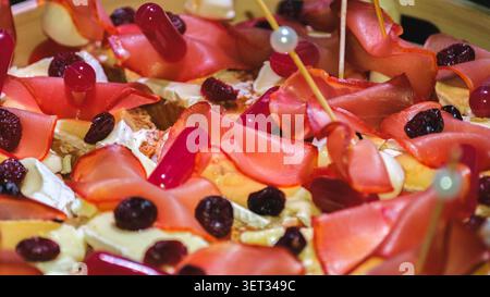 Eine handwerkliche Vorspeise mit geräuchertem Fleisch, cremigem Käse und getrockneten Beeren, die elegant für eine anspruchsvolle Party oder ein Catering arrangiert werden Stockfoto