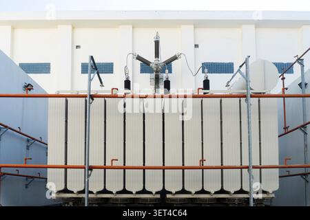 Ein großer Leistungstransformator mit Kühlrippen und Keramikisolatoren an einer elektrischen Unterstation Stockfoto