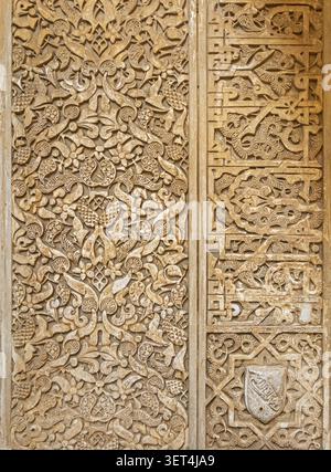 Eine detaillierte Ansicht von geschnitzten arabesken Blumenmustern und arabischer Kalligraphie-Schrift auf einer Gipswand in der Alhambra in Granada, Spanien Stockfoto